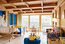 Das Babyzimmer für die Betreuung der Babys mit Babybetten, Babyspielsachen und Sitzmöglichkeiten im Familienhotel Wellness- & Familienhotel Egger in Saalbach Hinterglemm.