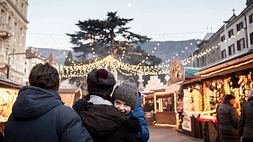 Der Weihnachtsmarkt mit der Familie ist ein echter Ausflugstipp im Winter in Südirol. Der Markt wird von Lichterketten geschmückt.