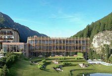 Das Familotel Bella Vista in Südtirol in den Bergen mit Pool, Liegewiese und modernem Holzgebäude vor bewaldeter Alpenlandschaft.