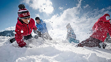Kinder spielen im Schnee im Winter und haben Spaß. Allgäu bietet sich für jeden Winterurlaub mit der Familie an.
