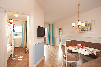 Der Wohnbereich vom Familienzimmer mit einer gemütlichen Sitzecke zum Essen und gemeinsam spielen im Familienhotel Das Hopfgarten in Tirol.
