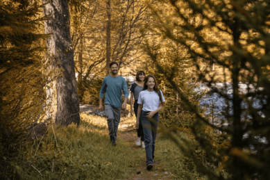 Familienhotel Bella Vista: Familie wandert durch einen herbstlichen Wald in Südtirol.