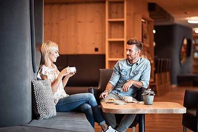 Eltern entspannen bei einer Tasse Kaffee in der Lounge des Familienhotels Family Home Alpenhof