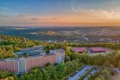 Luftaufnahme des Familienhotels Sonnenhügel bei Sonnenuntergang, eingebettet in die idyllische Landschaft des Bayerischen Waldes mit umgebenden Wäldern und sanften Hügeln.