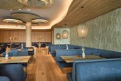 Stilvoller Restaurant- und Loungebereich im Hotel Zauchenseehof mit gemütlichen Sitznischen, blauen Polsterbänken, Holztischen und warmem Lichtdesign in moderner Alpenoptik.