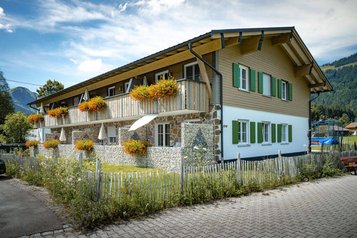 Appartementhaus Rohnenspitz mit traditionellem Charme und buntem Blumenschmuck am Familienhotel Krone im Allgäu.