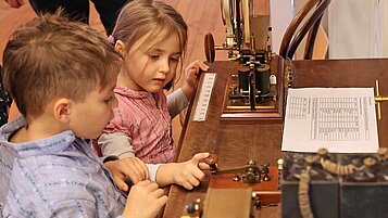 Zwei kleine Kinder sehen sich in einem historischen Museum in Bayern die Ausstellungsstücke sehr genau an..