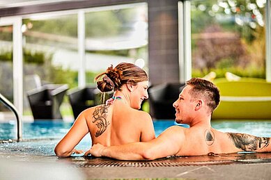 Eltern im Indoor-Schwimmbecken im Familienhotel Aigo welcome family in Oberösterreich