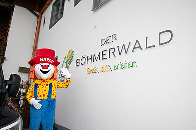 Maskottchen Happy steht vor dem Eingang des Familienhotels Der Böhmerwald.