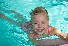 Glückliches Mädchen schwimmt im Pool des Familienhotels Gut Landegge im Emsland.