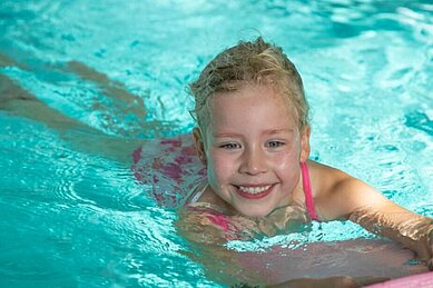 Glückliches Mädchen schwimmt im Pool des Familienhotels Gut Landegge im Emsland.