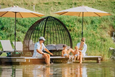 Familie entspannt im Sommerurlaub in Kärnten am Steg des Familienhotels