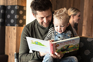 Ein Vater liest seinem Sohn aus einem Kinderbuch vor.