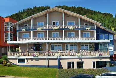 Außenansicht des Hotels Alpengasthof Hochegger im Sommer. Die Balkone vor der hellen Fassade sind mit schönen Blumenkästen dekoriert.