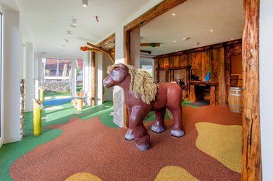 Kreativ gestalteter Indoor-Spielbereich mit großer Holzpferd-Figur und buntem Boden für Kinder im Hotel Engel im Schwarzwald