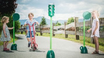 Kinder spielen Verkehrstraining im Landgut Furtherwirt, Lernspaß mit Roller und Ampelspiel auf dem Hof