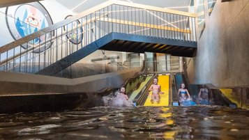 Drei Kinder rutschen fröhlich die bunte Trio Slide Rutsche im Alpenhotel Kindl im Sutbaital hinunter