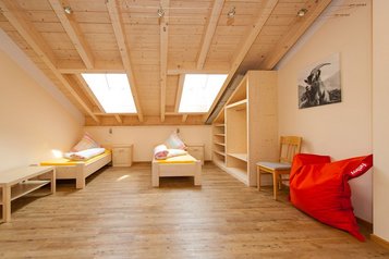 Helles Kinderzimmer mit zwei Einzelbetten und Holzdecke im Familienhotel Krone im Allgäu.