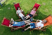 Jugendliche Kinder liegen im Liegestuhl im Garten und Verweilen gemeinsam im Familienhotel Landhuus Laurenz.