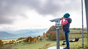 Wandern in der Rhön auf dem "Schöpfungsweg: Kind sieht durch ein Fernrohr ins Tal