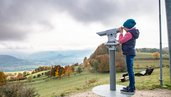 Wandern in der Rhön auf dem "Schöpfungsweg: Kind sieht durch ein Fernrohr ins Tal