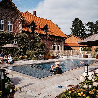 Familien planschen im Außenpool des Familienhotels Landhaus Averbeck in der Lüneburger Heide.
