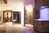 Moderner Adults-only-Wellnessbereich im Familienhotel Oberkarteis im Salzburger Land mit Steinoberflächen, beleuchtetem Eisbrunnen und Zugang zu Sauna- und Dampfbadbereich.