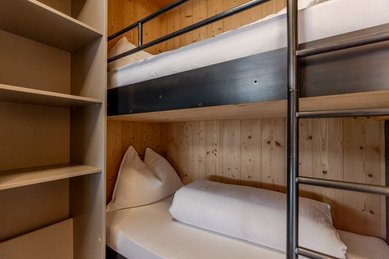 Gemütliches Kinderzimmer mit Stockbett im Familienhotel Almfamilyhotel Scherer, gestaltet in warmem Holzdesign.