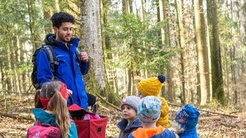 Einige Kinder und ein Kinderbetreuer im Outdoorclub im Wald im Landhaus zur Ohe im Bayerischen Wald. 