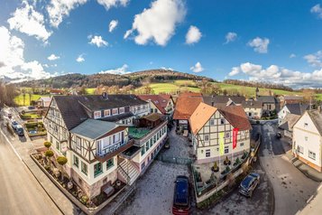 Luftaufnahme des Familienhotel Ottonenhof mit umliegenden Fachwerkhäusern und grüner Landschaft.
