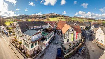 Luftaufnahme des Familienhotel Ottonenhof mit umliegenden Fachwerkhäusern und grüner Landschaft.