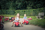 Zwei Kinder fahren Bobbycar auf der Bobbycar-Rennstrecke des Familienhotels Schreinerhof.