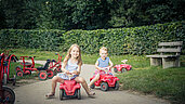 Zwei Kinder fahren Bobbycar auf der Bobbycar-Rennstrecke des Familienhotels Schreinerhof.