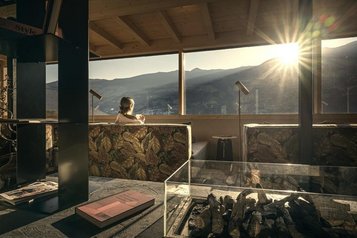 Ruhebereich im Familienhotel Mia Alpina in Tirol mit Liegefläche, großen Fenstern und Bergpanorama bei Sonnenlicht.