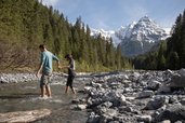 Familie wandert nahe dem Familienhotel Bella Vista in Südtirol an einem Bachbett mit Bergpanorama.