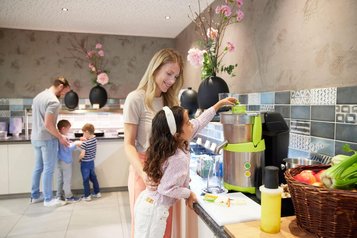 Familie bereitet frischen Saft am Frühstücksbuffet im Familienhotel Das Bayrischzell zu