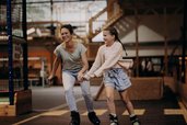 Eine Mutter fährt mit ihrer Tochter in der Erlebnishalle des Hotel Sonngastein im Salzburger Land Inlineskates.
