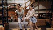Eine Mutter fährt mit ihrer Tochter in der Erlebnishalle des Hotel Sonngastein im Salzburger Land Inlineskates.