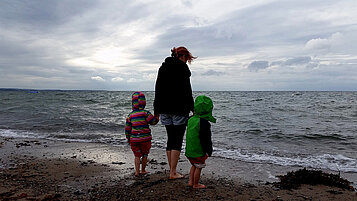 Mutter mit ihren beiden Kindern am Ostseestrand bei grauem Wetter.
