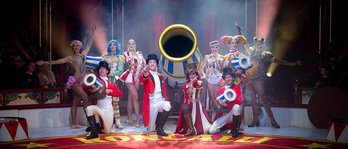 Zirkusensemble feiert in der Manege unter buntem Konfettiregen vor applaudierendem Publikum.
