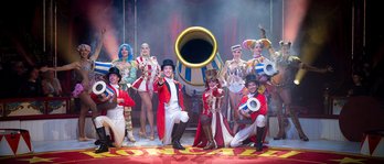 Zirkusensemble feiert in der Manege unter buntem Konfettiregen vor applaudierendem Publikum.