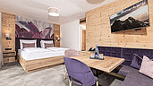 Großer Schlafbereich mit einem Doppelbett und einer Wohnecke im Galtenberg Family & Wellness Resort in Tirol.