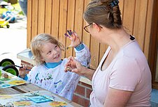 Junge malt gemeinsam mit einer Kinderbetreuuerin im Happy-Club des Familienhotel Landhuus Laurenz.