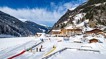 Winter Aufnahme von der Landschaft und der Kinderskischule vom Familienhotel Oberkarteis im Salzburger Land.