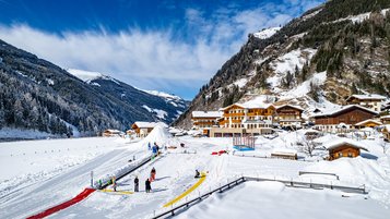 Winter Aufnahme von der Landschaft und der Kinderskischule vom Familienhotel Oberkarteis im Salzburger Land.
