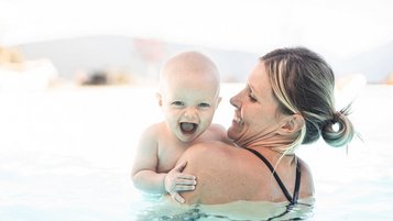 Mutter mit ihrem Baby im Pool im Family Home Alpenhof in Südtirol