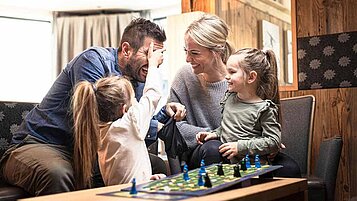 Eine Familie beim Brettspiel im Last-Minute Familienurlaub in einem Familotel