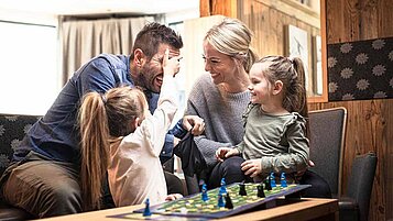 Eine Familie beim Brettspiel im Last-Minute Familienurlaub in einem Familotel
