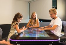 Drei Kinder spielen gemeinsam ein interaktives Tischspiel im Almfamilyhotel Scherer in Tirol