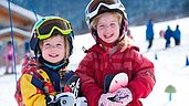 Fröhliche Kinder beim Skifahren im familienfreundlichen Skigebiet Pfronten im Allgäu.